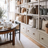 Calimia Home Tori Stool with three tapered legs and a round top, displayed on a shelf in a cozy living room.