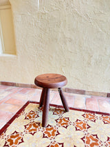 Calimia Home Tori Stool in dark wood with three tapered legs and a round top featuring traditional wedged joints.