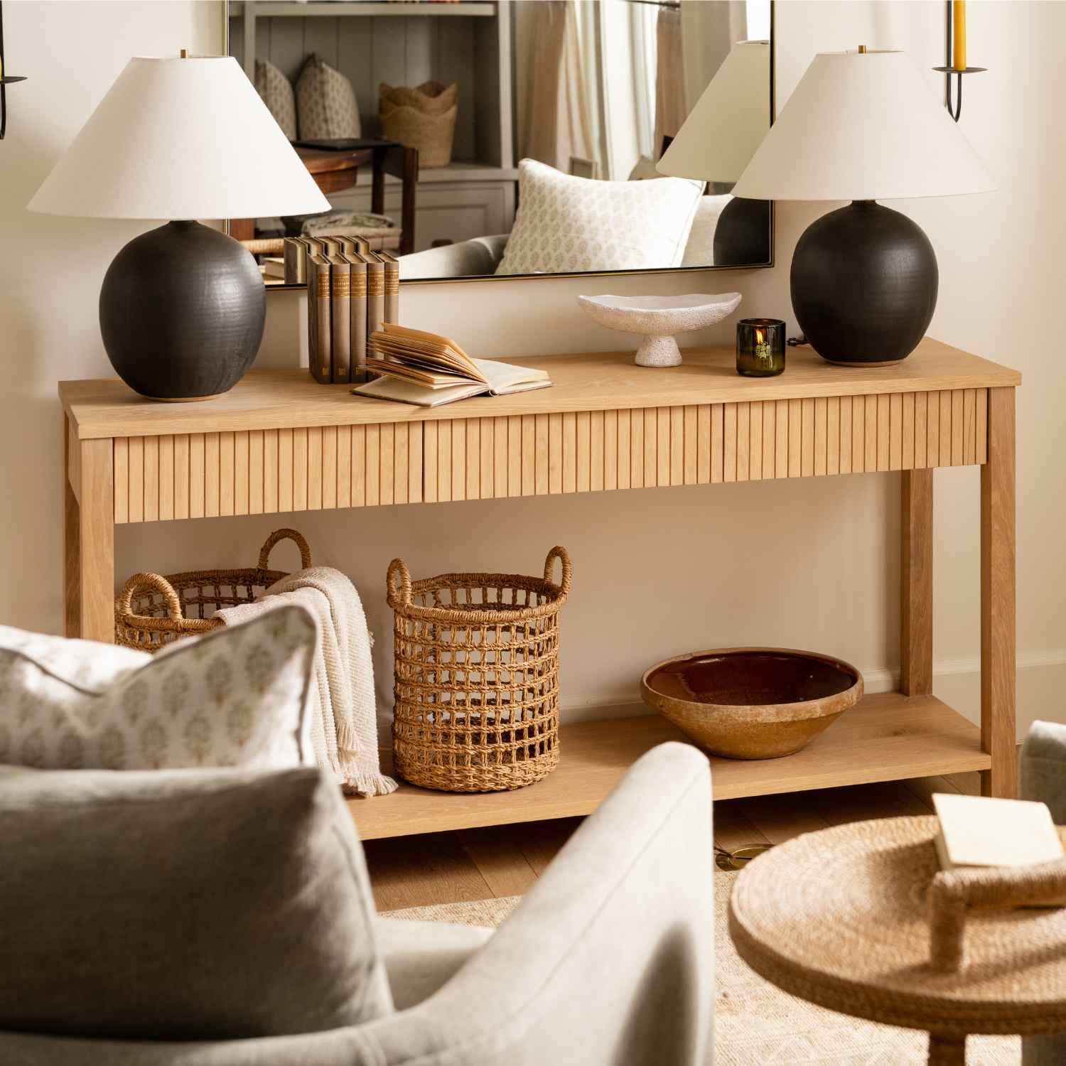 Fluted oak console with black ceramic lamps and woven baskets, styled for design trade clients