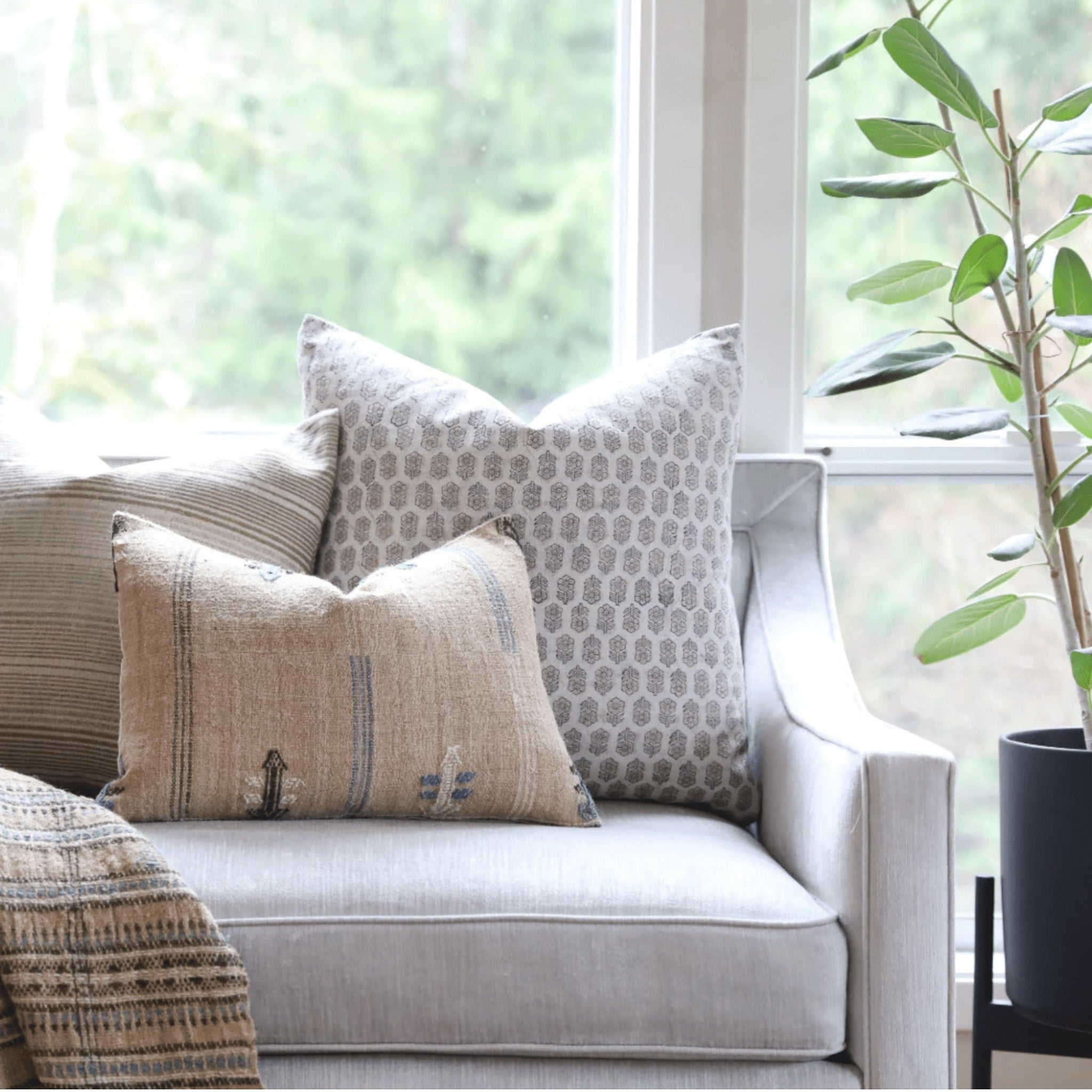Calimia Home Tulsi white floral block-printed linen pillow with feather insert on a neutral armchair