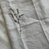 Close-up of the hand-embroidered branch motif on the Willow Stitch Apron, Belgian linen, One Bi One
