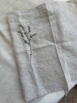 Full view of the Willow Stitch Apron laid flat, showing the linen body, embroidery detail, and long adjustable ties