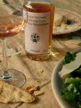 Persimmon Vinegar from Flamingo Estate joins a coupe of rosé and a green salad with shaved cheese on a linen-set table at golden hour.